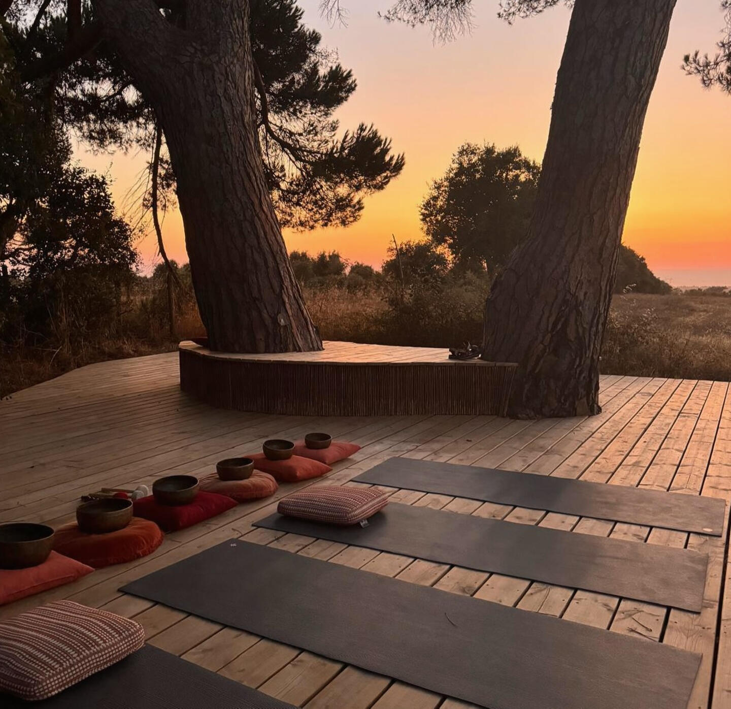 Outdoor wooden deck at sunset prepared for yoga, meditation and breathwork sessions during the 5Rhythms & Plant Medicine Retreat in Alentejo, Portugal.